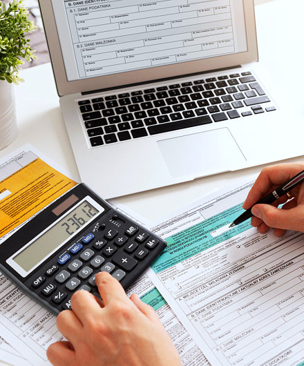 man writing on a document while calculating